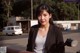 A woman in a black blazer standing next to a motorcycle.