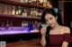 A woman sitting at a bar holding a martini glass.