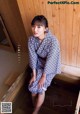 A woman in a blue and white kimono sitting in a bathtub.