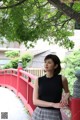 A woman standing on a red bridge in a park.