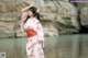 A woman in a pink kimono standing by a body of water.