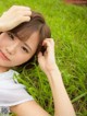 A young woman laying in the grass with her hands on her head.