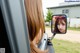 A woman is looking in the rear view mirror of a car.