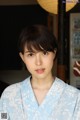 A woman in a blue kimono poses for a picture.