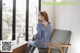 A woman sitting on a chair in front of a window.