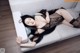 A woman laying on a white couch wearing a black lingerie.