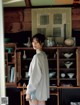 A woman standing in front of a book shelf in a room.