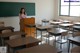 A woman standing at a podium in front of a blackboard.