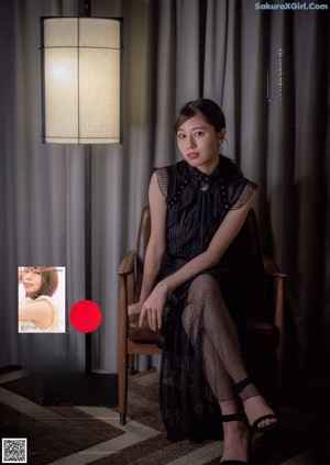 A woman sitting in a chair in front of a lamp.