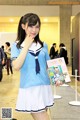 A woman in a school uniform holding a magazine.