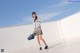 A woman in a school uniform is walking on a tiled floor.