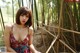 A woman in a red dress sitting on a bamboo fence.